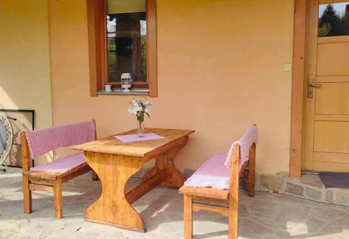 a wooden table with two chairs and a vase of flowers at Country House Liptov in Svätý Kríž