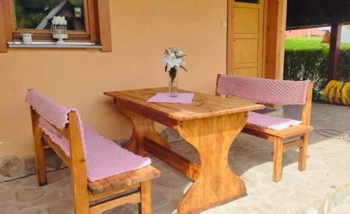 a wooden table with two chairs and a vase with flowers on it at Country House Liptov in Svätý Kríž