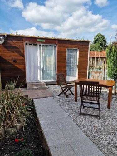un patio avec une table et des chaises et un bâtiment dans l'établissement Tiny House La Cabane du Bohémien, à Saint-Quentin