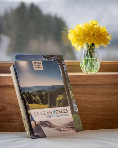 a book sitting on a table next to a vase with yellow flowers at L'Alcôve - Chalet avec Piscine in Xonrupt-Longemer