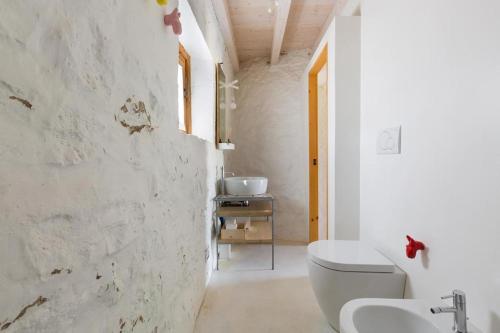 een witte badkamer met een toilet en een wastafel bij Trullo Salento in Corigliano dʼOtranto