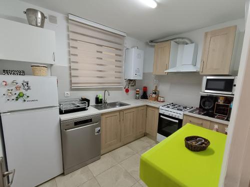 a kitchen with a white refrigerator and a green table at Apartamento confort I in La Seu d'Urgell