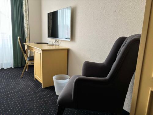 a room with a desk and a television and chairs at Hotel & Restaurant Schönau in Peine