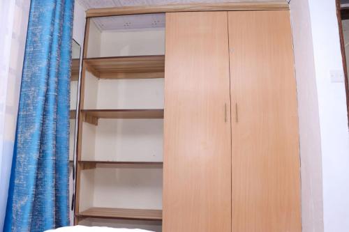 a wooden cabinet in a bedroom with a blue curtain at Lulu Stays 1 Bedroom in Nyahururu