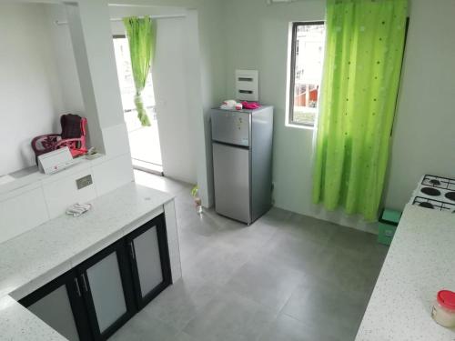 a kitchen with a stainless steel refrigerator and green curtains at Cosy apartment on the 1st floor in Curepipe