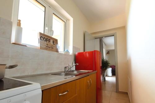 eine Küche mit einer Spüle und einem roten Kühlschrank in der Unterkunft Skafidia Seaview Retreat - Orpheas Seaview Home in Skafidia