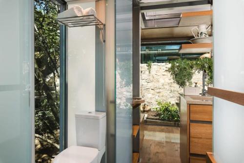 a bathroom with a toilet and a large window at Luxury TreeHouse - A breath away from the beach in Loutrákion
