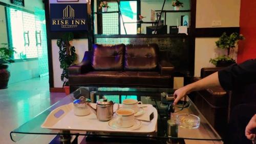 a coffee table with a tray of coffee cups on it at Hotel Rise Inn in Karachi