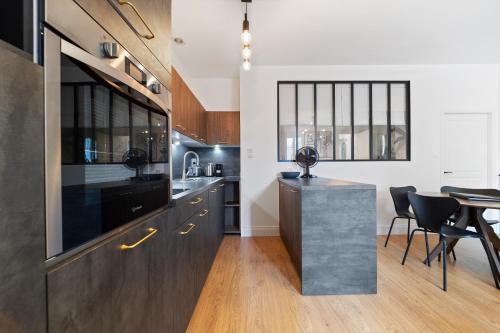 une cuisine avec des armoires noires, une table et des chaises dans l'établissement Charme & Tranquillité : Jardin de l’Arquebuse/Gare, à Dijon