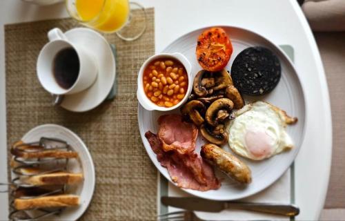 a plate of breakfast food with eggs bacon beans and a cup of coffee at Old Daltongate House in Ulverston