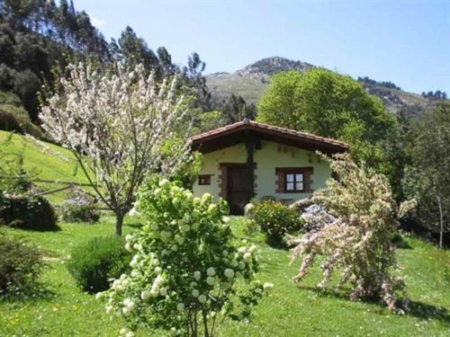 a small house in a field with trees and bushes at Los Acebos de Pena Cabarga in Sobremazas