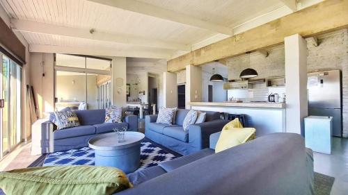 a living room with blue couches and a kitchen at Under Milkwood in Chintsa