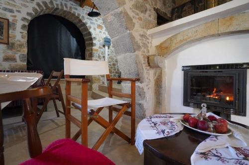 sala de estar con chimenea, mesa y sillas en Unwind and Relax at the Vilaeti 1871 Retreat, en Agios Konstantinos