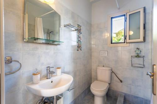 a bathroom with a sink and a toilet and a mirror at Kitries Summer Getaway - Eden Comfy Suite in Kitriaí
