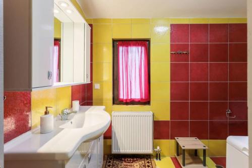 Baño amarillo y rojo con lavabo y espejo en Arcadia Getaway - Levidi Sani 11 Suite, en Levidhion