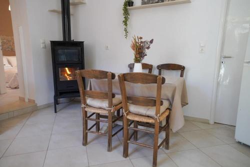 mesa de comedor con 2 sillas y chimenea en Vilaeti Havgas Getaway - Cretan Cozy Home, en Agios Konstantinos
