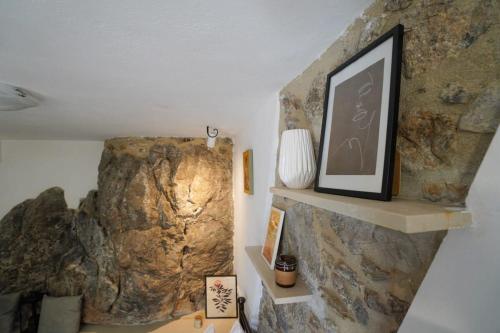 a room with a rock wall with a picture on a shelf at Vilaeti Stone House - Cretan Cozy Nest in Agios Konstantinos