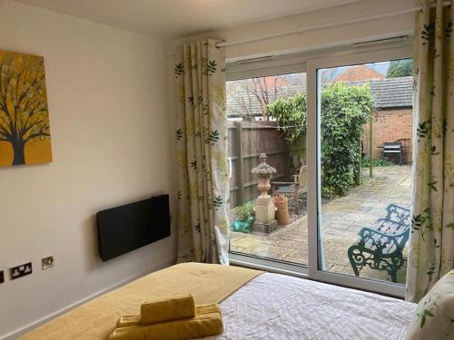 Park Cottage - Cosy 1 bedroom في Spinney Hill: غرفة نوم بسرير وباب زجاجي منزلق