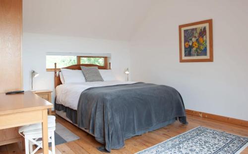 a bedroom with a bed and a desk in it at Dartmoor Barn on North Hessary Tor in Yelverton