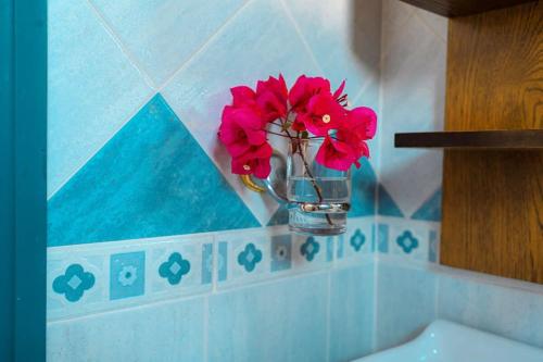 a vase filled with red flowers in a bathroom at Cycladic Bliss - Uncovering Paros Seaview Gem in Drios