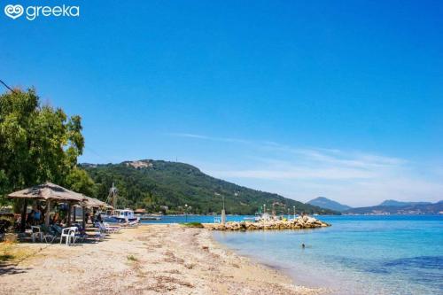 a beach with chairs and tables and the water at Serenity Suite in Corfu - Escape to Paradise in Kouspádes
