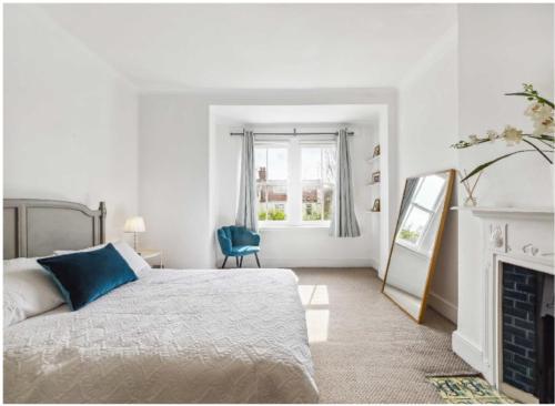 a white bedroom with a bed and a fireplace at Arragon in Streatham Vale