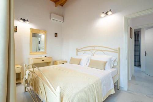 a white bedroom with a white bed and a mirror at Mani Stone Built Home A breath Away to the Sea in Stoupa