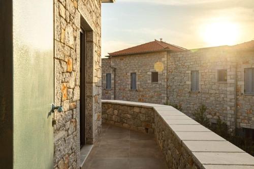 a walkway leading to a building with a stone wall at Mani Stone Built Home A breath Away to the Sea in Stoupa