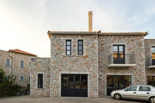 a stone building with a car parked in front of it at Mani Stone Built Home A breath Away to the Sea in Stoupa
