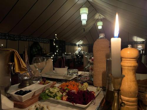 a table with a candle and a plate of food at Merzouga Stars Luxury Camp in Merzouga