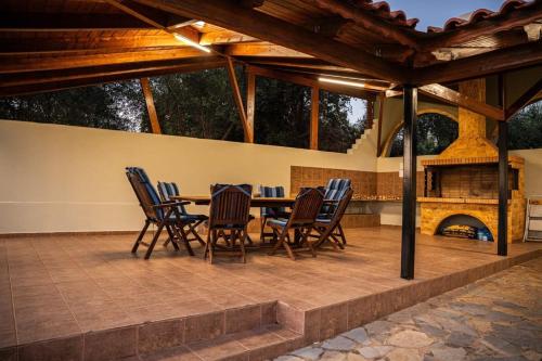 un patio con mesa, sillas y chimenea en Filiatra's Cozy Haven A Peaceful Escape in Nature, en Filiatra