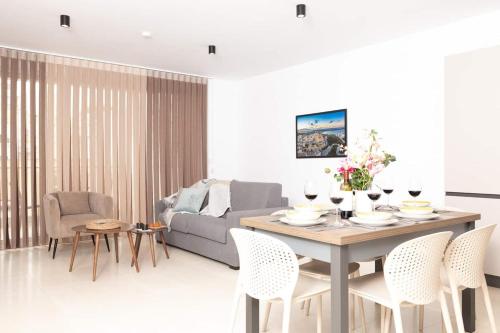 a living room with a table with chairs and a couch at 2Bed flat w shared heated pool in MLH by Homely! in Mellieħa