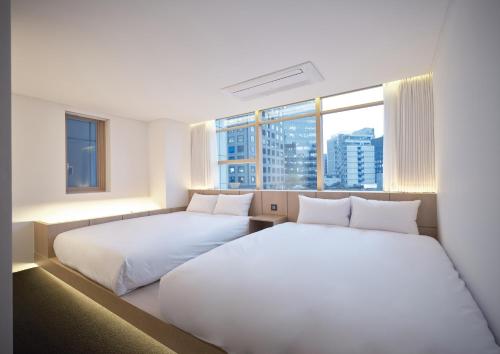 two beds in a room with a large window at UH Suite Seoul Deoksugung in Seoul