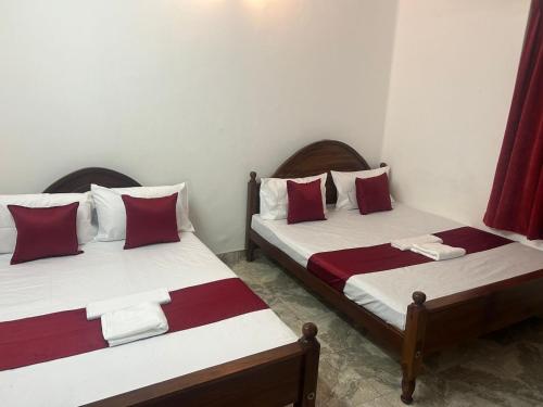 2 letti in una camera con cuscini rossi e bianchi di MercuryFM 109 Guest House - Jaffna Temple road 77 a Jaffna