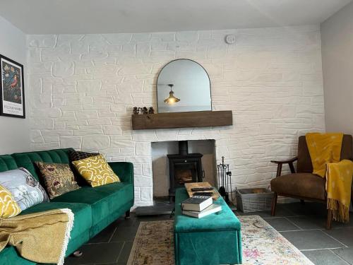 a living room with a green couch and a fireplace at Charming 2-Bed House in Llansteffan in Llanstephan