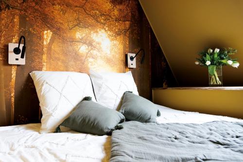Suite & SPA à La Ferme 1802 في Sainghin-en-Mélantois: سرير بملاءات بيضاء و مزهرية من الزهور
