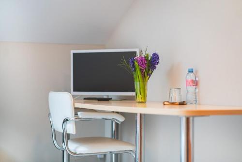 a desk with a computer and a vase of flowers on it at ARIBĖ Hotel Klaipėda, Free parking in Klaipėda