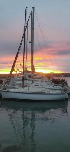 a sailboat docked in the water with a sunset in the background at Voilier en bord de mer 55€ par nuit in Marseillan