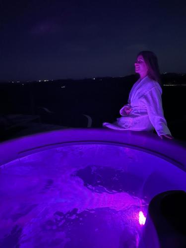 a woman sitting on the edge of a hot tub at night at Terasse Jeruzalem Apartments in Hermanci