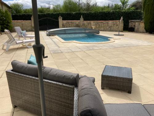 une terrasse avec un canapé, un parasol et une piscine dans l'établissement La Grange, à Blanzay