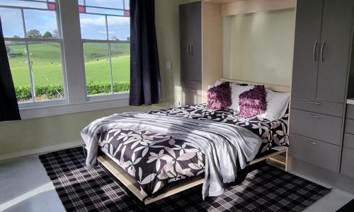 ein Schlafzimmer mit einem Bett mit lila Kissen in der Unterkunft Sunshine Studio in Hamilton
