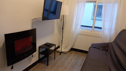 una pequeña sala de estar con TV y cama en Apartamento Forn Vell en Sant Feliu de Guixols