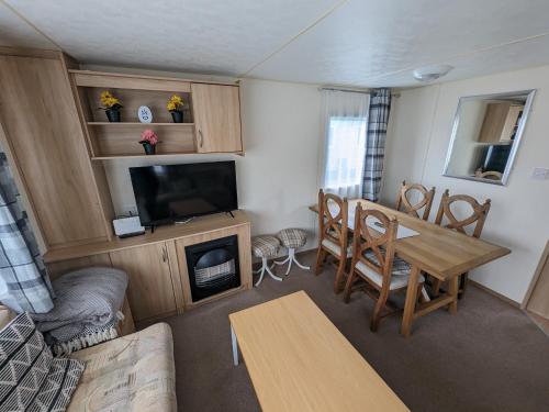 a living room with a table and a dining room at 3 Bedroom Caravan, Sleeps 8 Lyons Lido Beach in Prestatyn