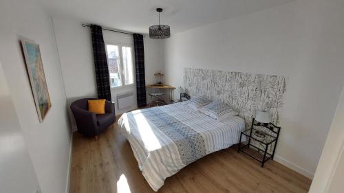 a bedroom with a bed and a chair in it at Maison au coeur de Meschers - proche des plages in Meschers-sur-Gironde
