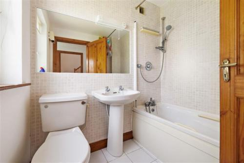 ein Badezimmer mit einem Waschbecken, einem WC und einer Badewanne in der Unterkunft Brittas Bay Village No 7 in Brittas Bay