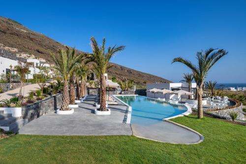 a resort with a swimming pool and palm trees at Palm Island Suites in Imerovigli