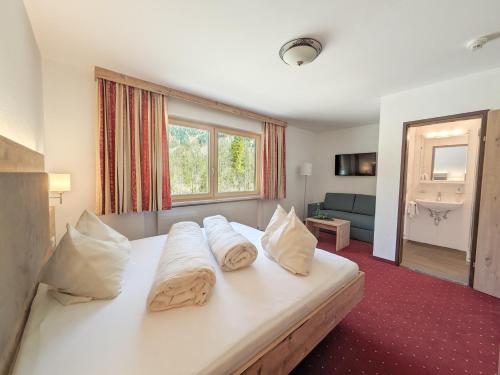 a bedroom with a large white bed with pillows at Hotel Forelle in Plansee