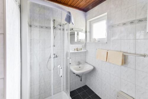 a white bathroom with a shower and a sink at Ferienhäuser Angela in Unternarrach