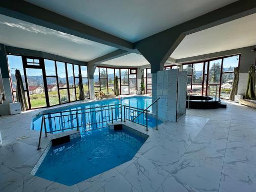 a large swimming pool in a building with windows at Vlasic Odmor - Villa Wellnes & spa in Vlasic
