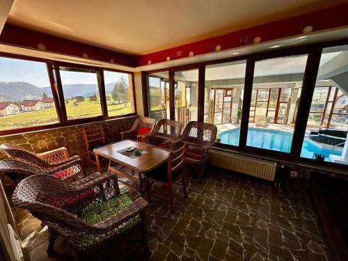 a room with a table and chairs and a swimming pool at Vlasic Odmor - Villa Wellnes & spa in Vlasic